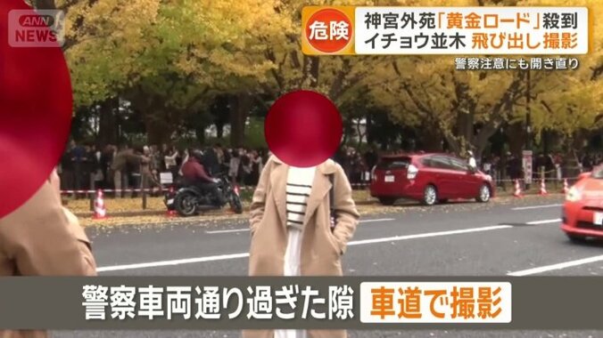 警察車両が通り過ぎた隙に撮影を試みる女性