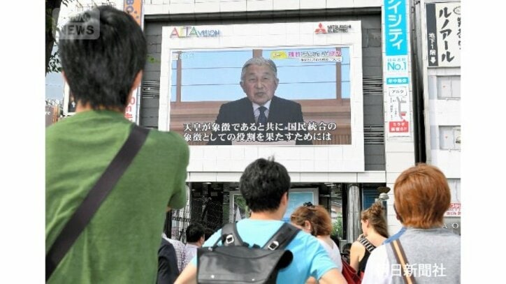 街頭の大画面で天皇陛下のお気持ちを示したビデオメッセージが流され、通りかかった人が見上げていた＝2016年8月8日、東京・新宿、朝日新聞社提供