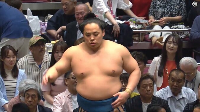 琴栄峰の左ヒジ越しに白Tシャツ黒ジャケットの長江健次