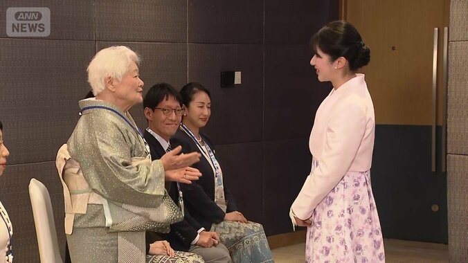 薄桃色のジャケットに淡い模様のワンピース