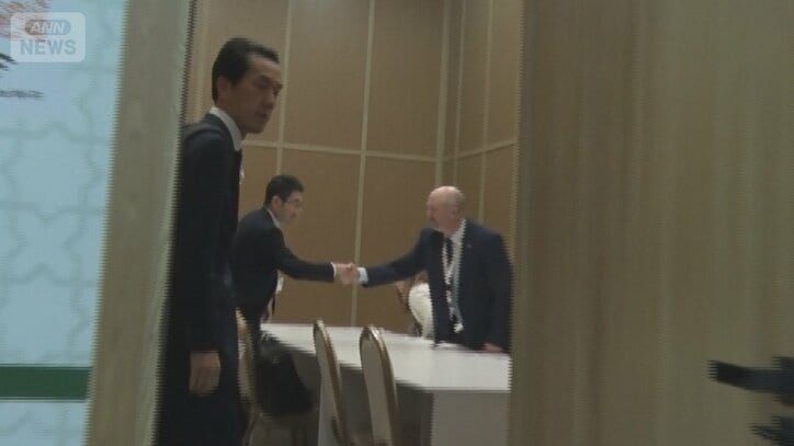 「EXIT」と書かれた会議室の中で日本代表団がアメリカ代表団と握手していた