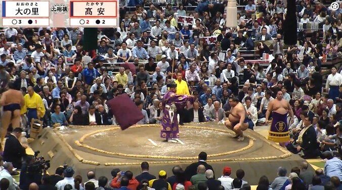 館内を舞う座布団。頭を両手で覆う観客も