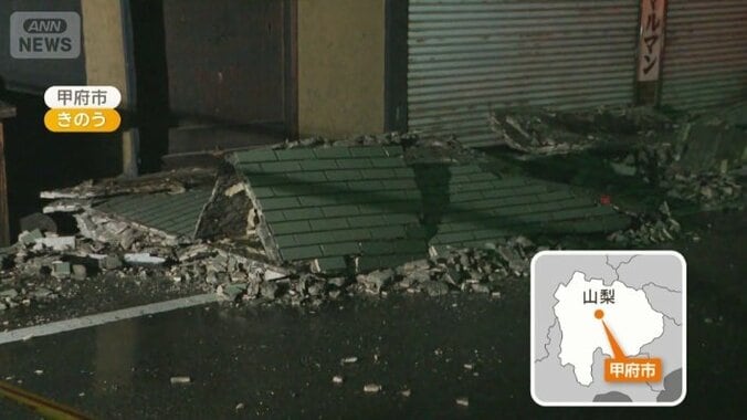 家屋の壁が崩れ道路に残骸が散らばる