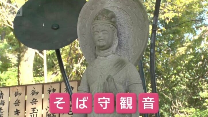 左手には「そばの実」、右手には「そばつゆが入ったとっくり」を持っている