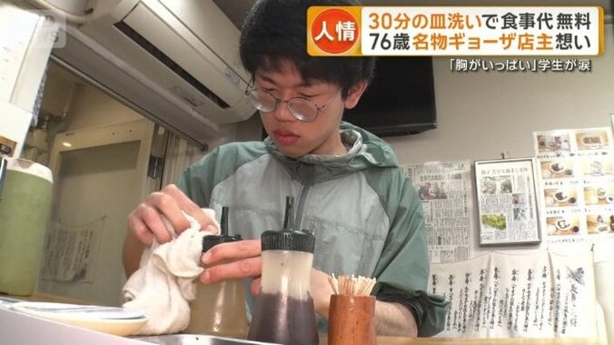 テーブルの調味料を拭く男子学生