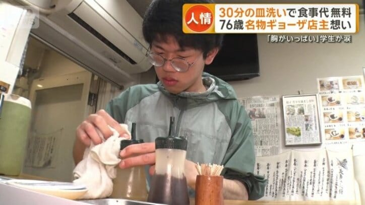 テーブルの調味料を拭く男子学生