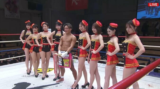 トロフィーを股間に当てラウンドガールと記念撮影