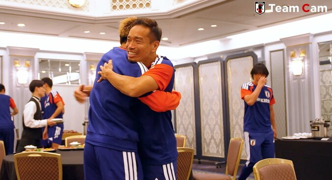 ハグ中に中村コーチが横切る