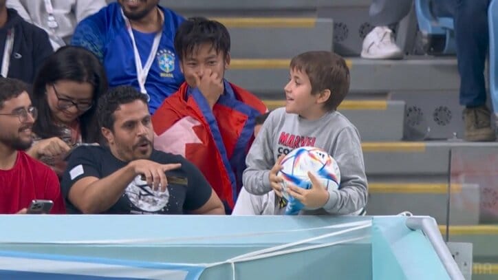 残念ながら“お持ち帰り禁止”スタンドに飛び込んだワールドカップ・ハイテク公式球を手に喜ぶ少年