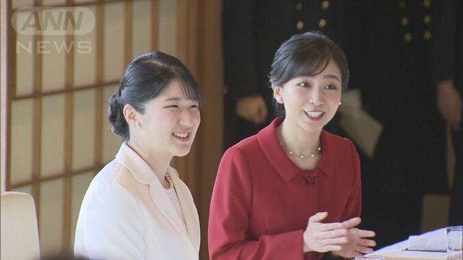 それぞれ白と赤の洋服を着て隣に座り、笑顔で懇談